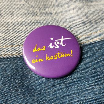 Ansteckbutton Das IST ein Kostüm / lila auf Jeans