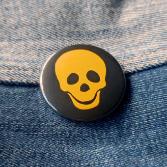 Ansteckbutton Totenkopf gelb auf Jeans