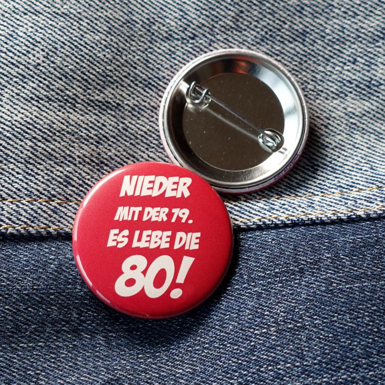 Ansteckbutton Nieder mit der 79 - es lebe die 80 auf Jeans mit Rückseite