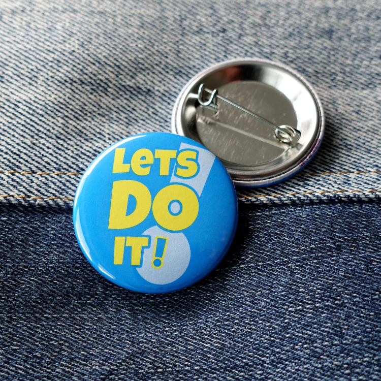 Ansteckbutton Lets do it! auf Jeans mit Rückseite