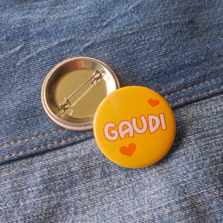 Ansteckbutton Gaudi gelb auf Jeans mit Rückseite