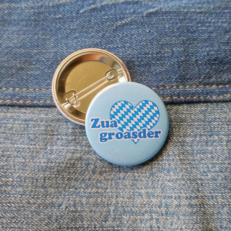Ansteckbutton Zuagroasder auf Jeans mit Rückseite